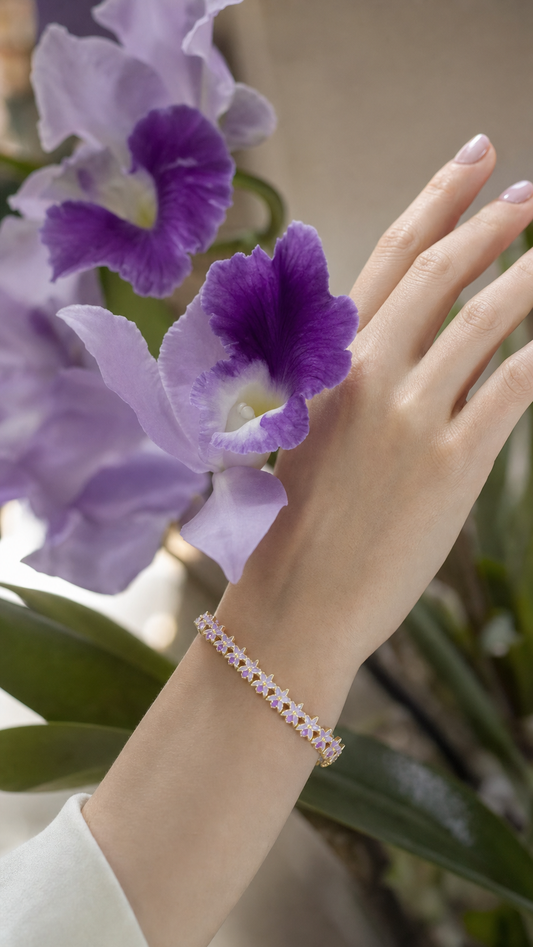 La Colombiana Collection Lavender Cattleya 14k Gold Bangle on wrist near real Cattleya orchid bloom - Orchidique