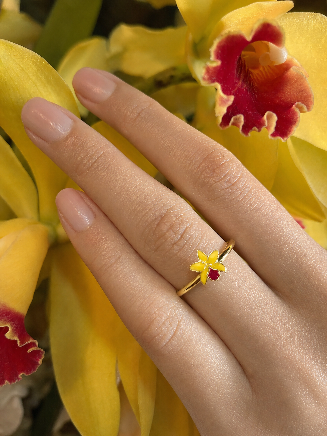 La Colombiana Collection Yellow & Red Cattleya Orchid Ring on hand near orchid petals - Orchidique