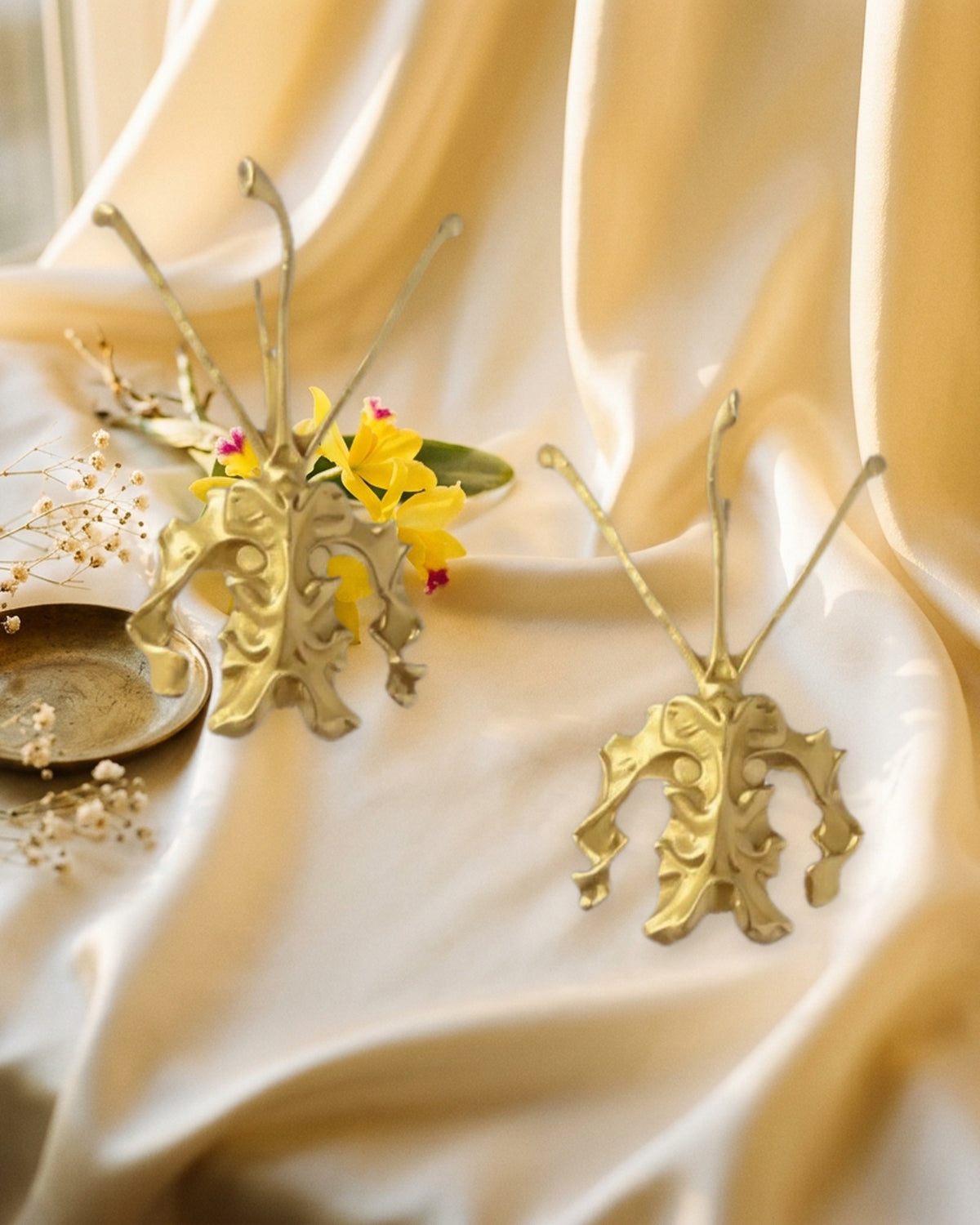 Psychopsis Butterfly Orchid earrings pair styled on blush silk with Cattleya orchid — Orchidique