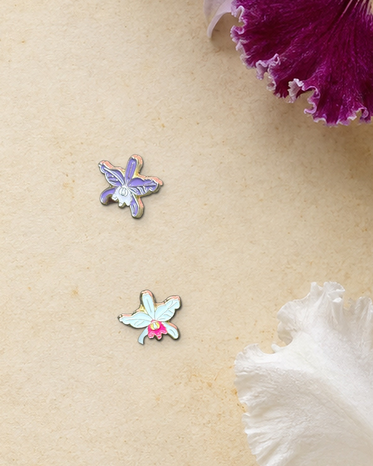 Purple and White mini Cattleya jenmanii enamel pins on an antique botanical Cattleya print beside fresh jenmanii blooms