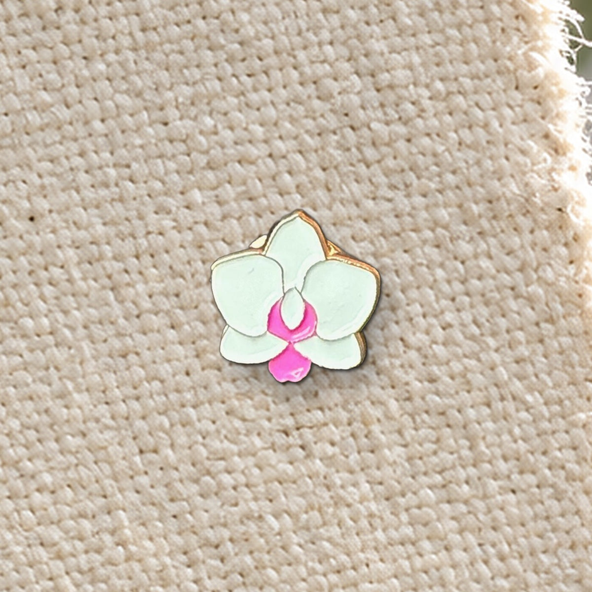 Close-up of the 14mm white and pink mini Phalaenopsis enamel pin on canvas