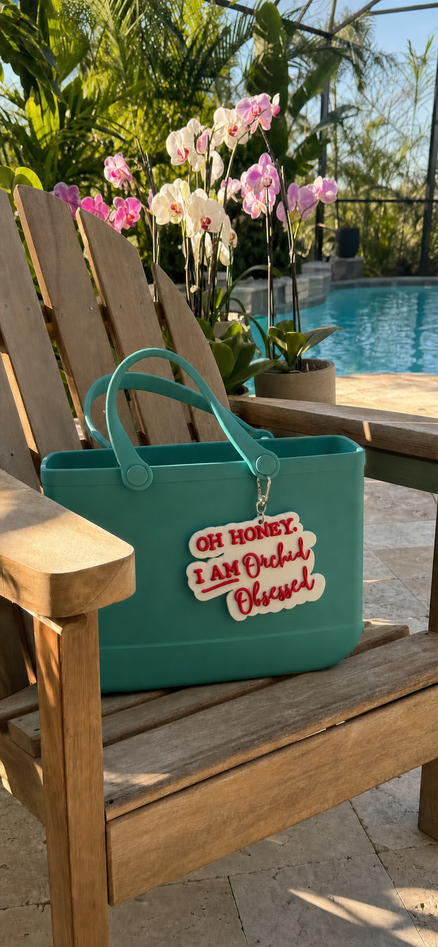 Oh Honey I'm Orchid Obsessed charm on teal beach tote poolside with pink and white orchids - Orchidique